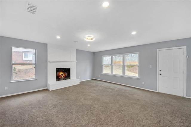 unfurnished living room with carpet floors, a fireplace, and a healthy amount of sunlight