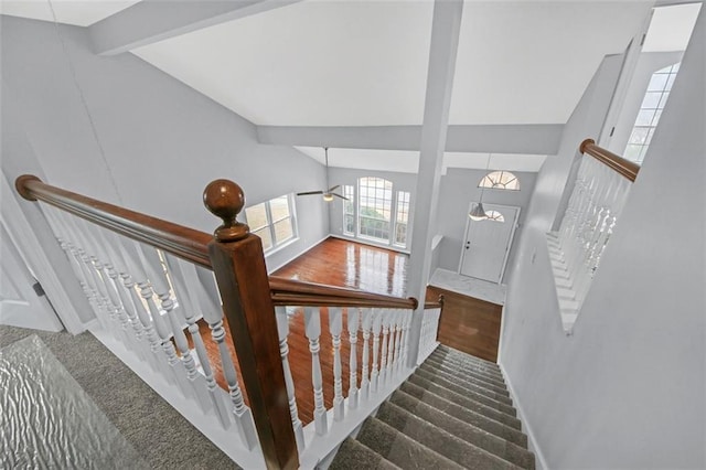 staircase with beam ceiling, high vaulted ceiling, and carpet