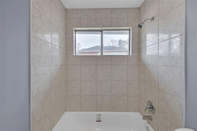 bathroom with tiled shower / bath combo and toilet