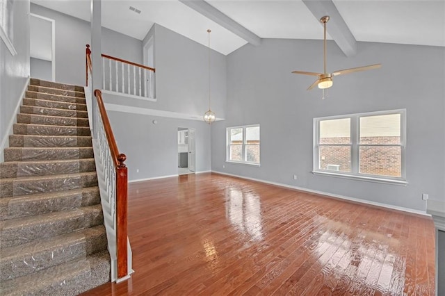 unfurnished living room featuring hardwood / wood-style flooring, ceiling fan, high vaulted ceiling, and beam ceiling