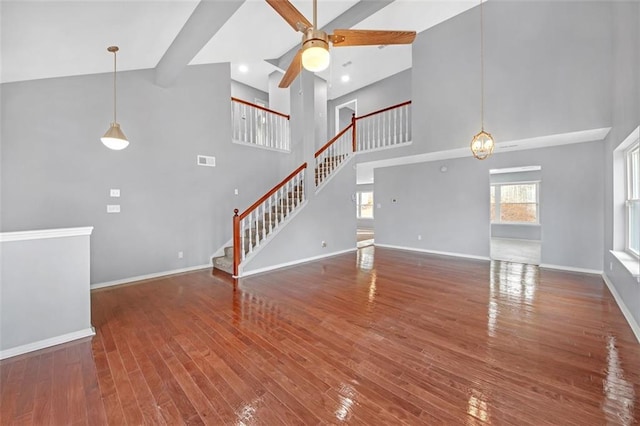 unfurnished living room featuring ceiling fan, a towering ceiling, and dark hardwood / wood-style flooring