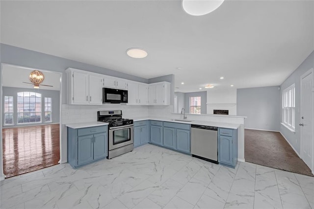 kitchen with sink, stainless steel appliances, white cabinets, and blue cabinets