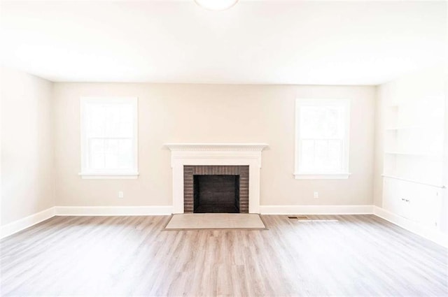 unfurnished living room with a fireplace, plenty of natural light, and light wood-type flooring