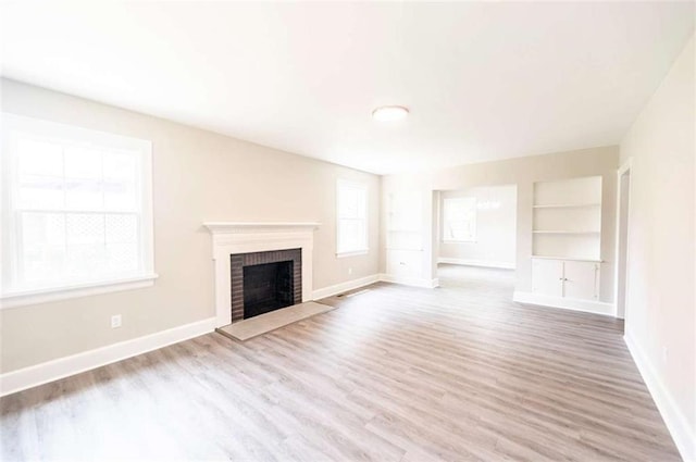 unfurnished living room with built in shelves, light hardwood / wood-style flooring, and a fireplace