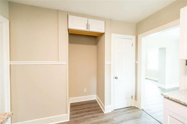 interior space with light stone counters, white cabinets, and light hardwood / wood-style flooring