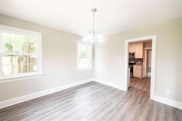 unfurnished dining area with light wood-type flooring and an inviting chandelier