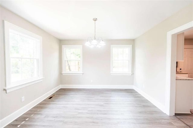 unfurnished dining area featuring a chandelier and light hardwood / wood-style flooring