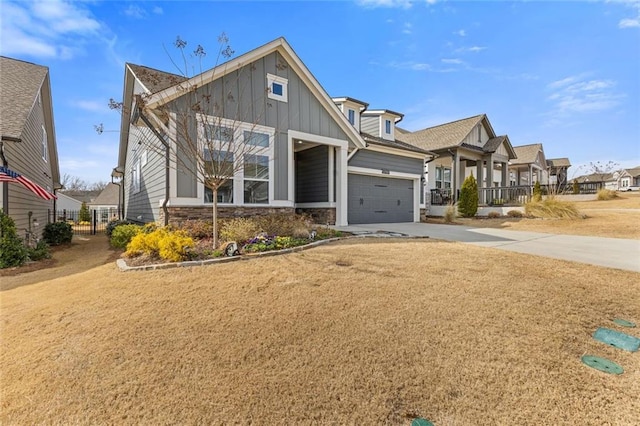 craftsman-style home with an attached garage, driveway, stone siding, board and batten siding, and a front yard