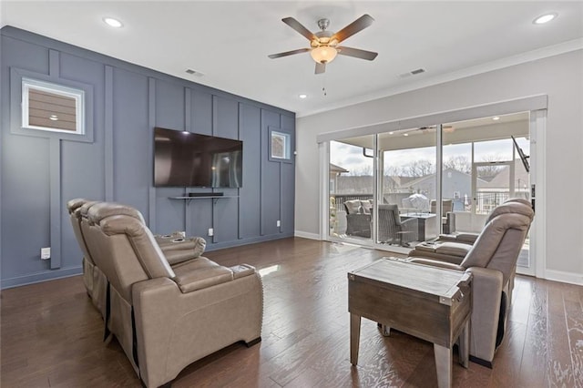 living room with visible vents, a ceiling fan, dark wood-style floors, ornamental molding, and a decorative wall