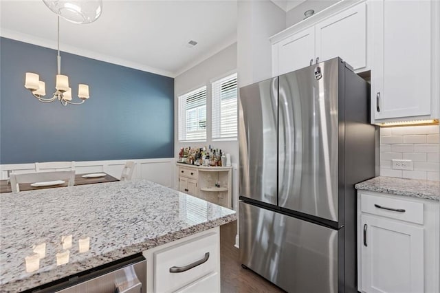 kitchen featuring wine cooler, light stone counters, freestanding refrigerator, crown molding, and white cabinetry