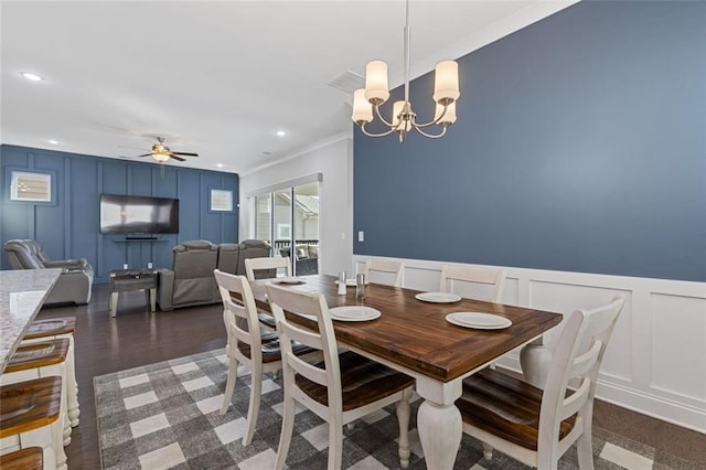 dining room with recessed lighting, dark wood-type flooring, crown molding, a decorative wall, and ceiling fan with notable chandelier
