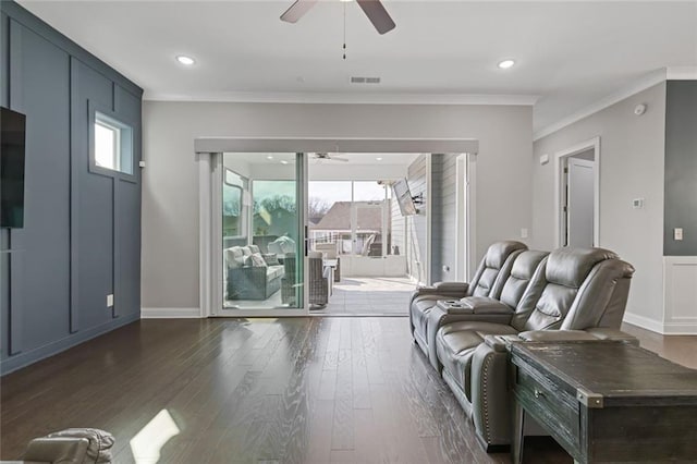 living room with ornamental molding, dark wood finished floors, visible vents, and ceiling fan
