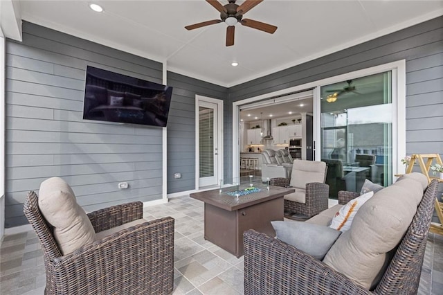 view of patio / terrace with a ceiling fan and an outdoor living space with a fire pit