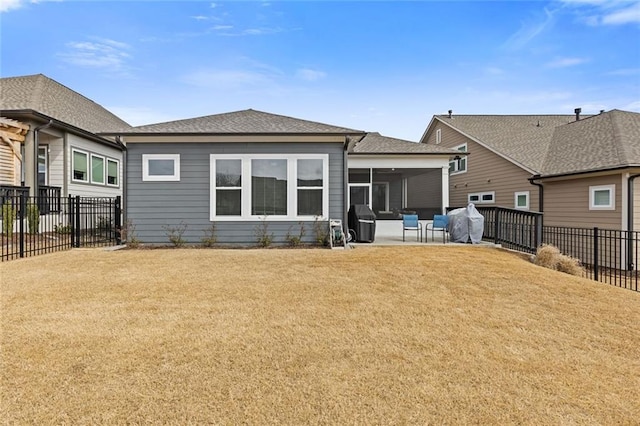 rear view of property featuring a sunroom, a fenced backyard, a lawn, and a patio