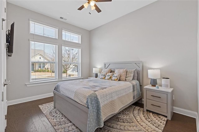 bedroom featuring a ceiling fan, visible vents, baseboards, and wood finished floors