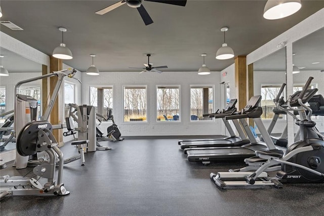 exercise room featuring visible vents, ceiling fan, and brick wall