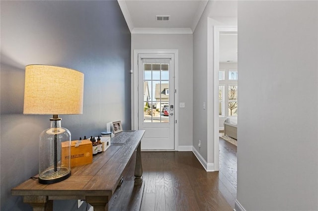 doorway featuring dark wood-style floors, ornamental molding, visible vents, and baseboards