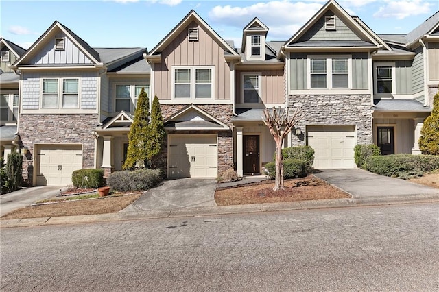 multi unit property featuring driveway, stone siding, board and batten siding, and an attached garage