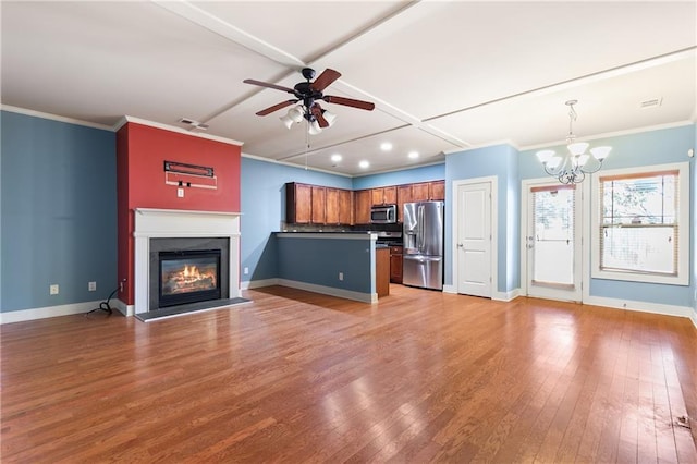 kitchen with light wood-style flooring, stainless steel appliances, open floor plan, hanging light fixtures, and brown cabinetry