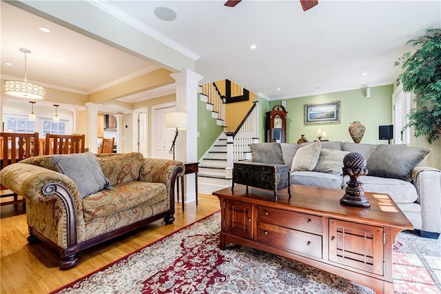 living room featuring a healthy amount of sunlight, decorative columns, crown molding, and wood finished floors