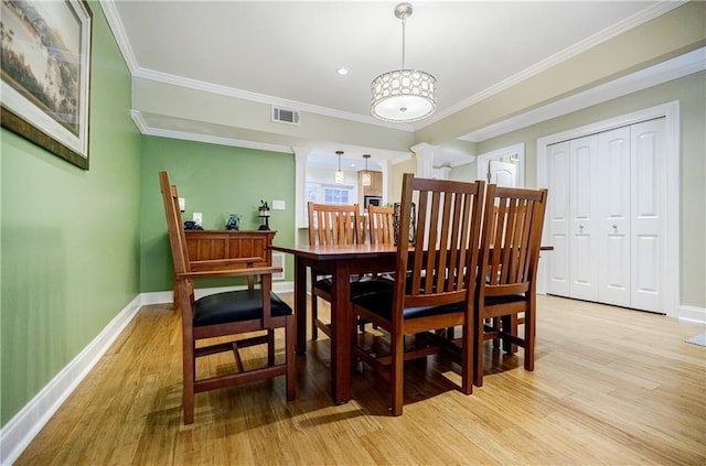 dining room with ornamental molding, light wood-type flooring, visible vents, and baseboards