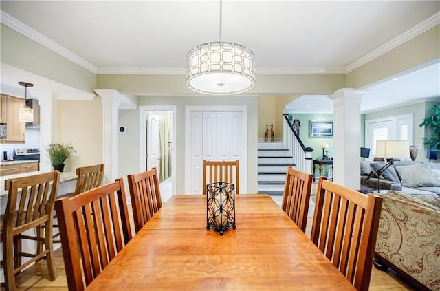 dining room featuring stairs, ornamental molding, light wood-style floors, and ornate columns