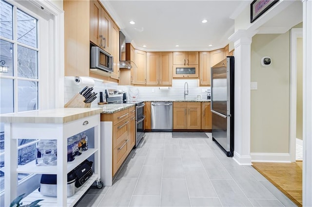 kitchen featuring tasteful backsplash, baseboards, light stone countertops, stainless steel appliances, and a sink