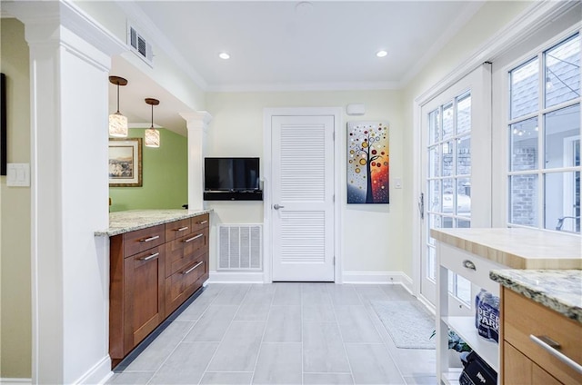 kitchen featuring crown molding, visible vents, light stone counters, and decorative light fixtures