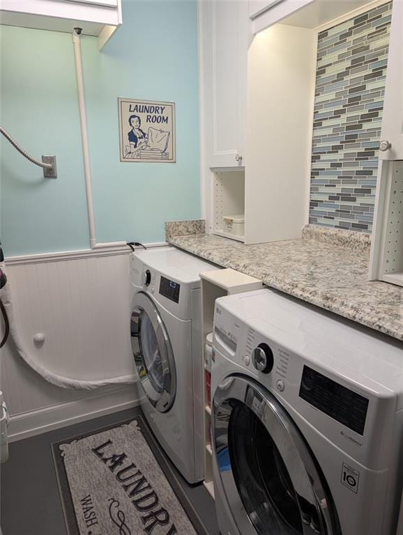 washroom with a wainscoted wall, laundry area, and separate washer and dryer