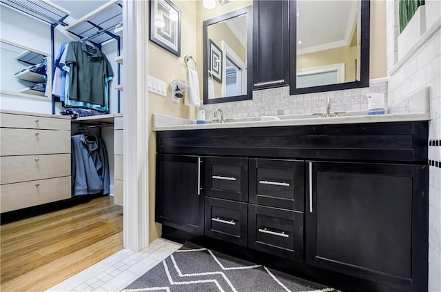 full bathroom featuring double vanity, wood finished floors, backsplash, and crown molding