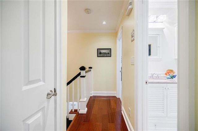 corridor with a sink, ornamental molding, dark wood finished floors, and baseboards