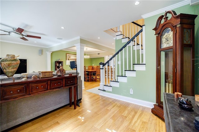 entryway with decorative columns, a ceiling fan, stairs, crown molding, and light wood-style floors