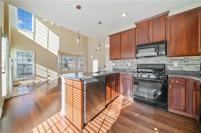 kitchen with black appliances, hardwood / wood-style flooring, a sink, a peninsula, and decorative backsplash