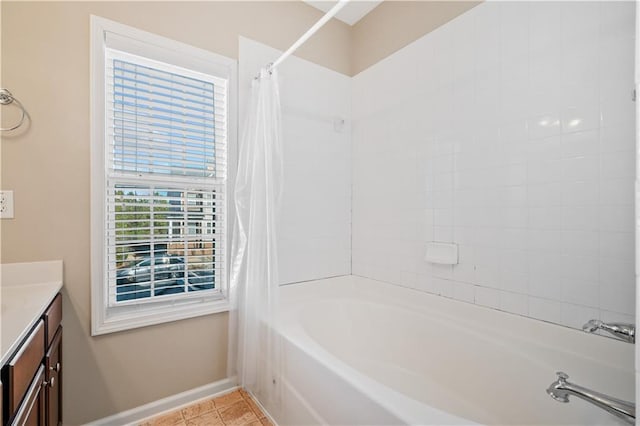 full bath with tile patterned floors, vanity, baseboards, and shower / bath combo