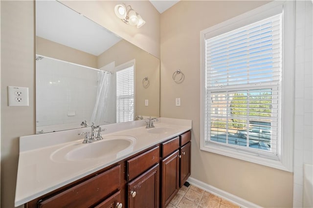 full bath with a healthy amount of sunlight, baseboards, and a sink