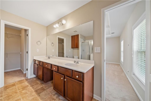 full bathroom with a sink, a walk in closet, double vanity, and a shower stall