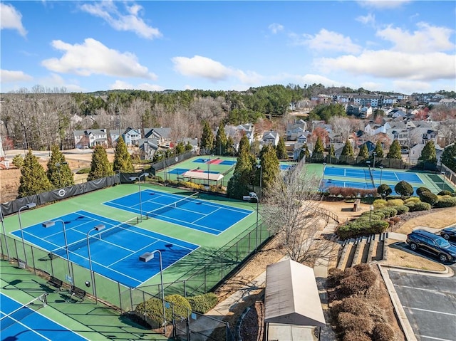 view of tennis court with a residential view and fence