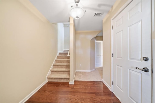 staircase featuring wood finished floors, baseboards, and visible vents