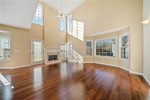 unfurnished living room featuring a ceiling fan, a healthy amount of sunlight, wood finished floors, and a fireplace