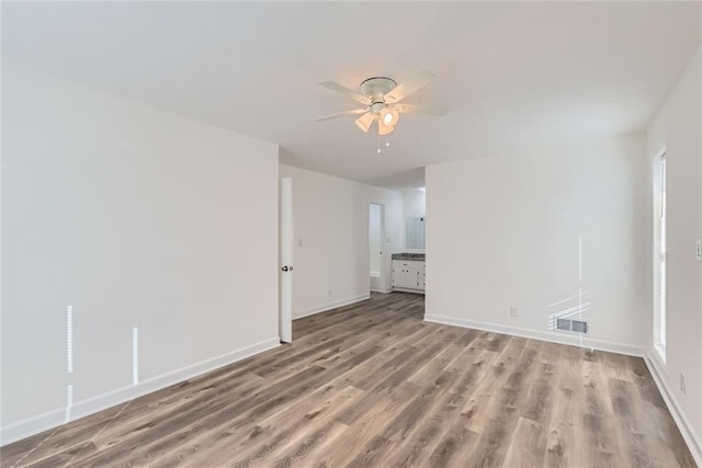 unfurnished room with baseboards, visible vents, ceiling fan, and wood finished floors