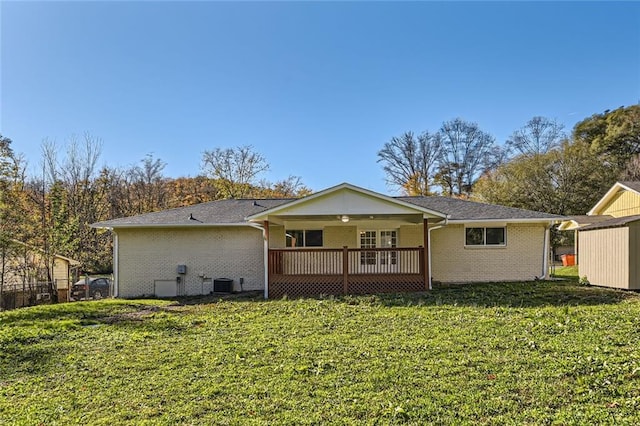 back of property with brick siding, a yard, a wooden deck, and central AC unit