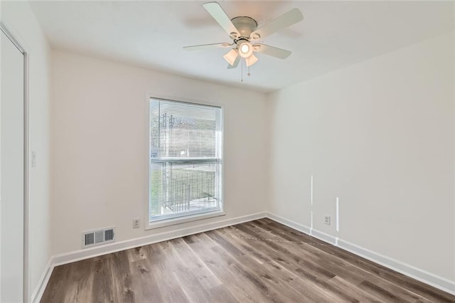 empty room with a ceiling fan, baseboards, visible vents, and wood finished floors