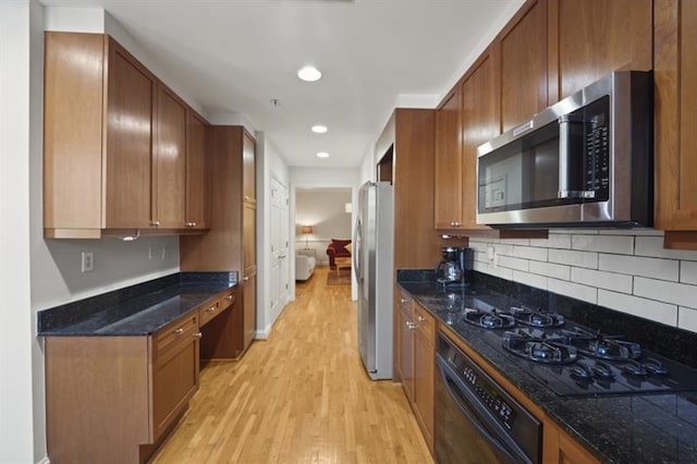 kitchen featuring light wood-type flooring, black appliances, brown cabinets, and built in desk