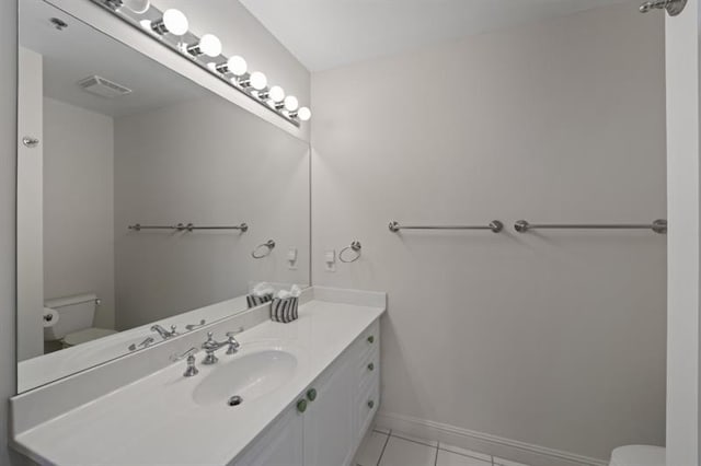 half bath with visible vents, toilet, vanity, baseboards, and tile patterned floors