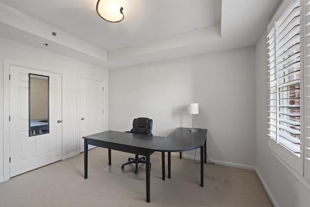 office area with plenty of natural light, a tray ceiling, baseboards, and light colored carpet