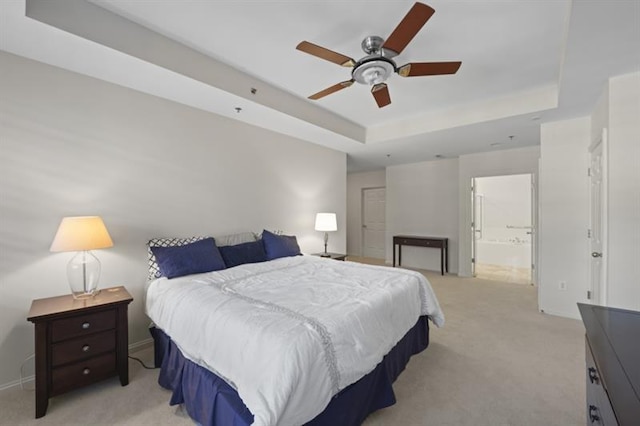 bedroom featuring baseboards, ensuite bathroom, a raised ceiling, and light colored carpet