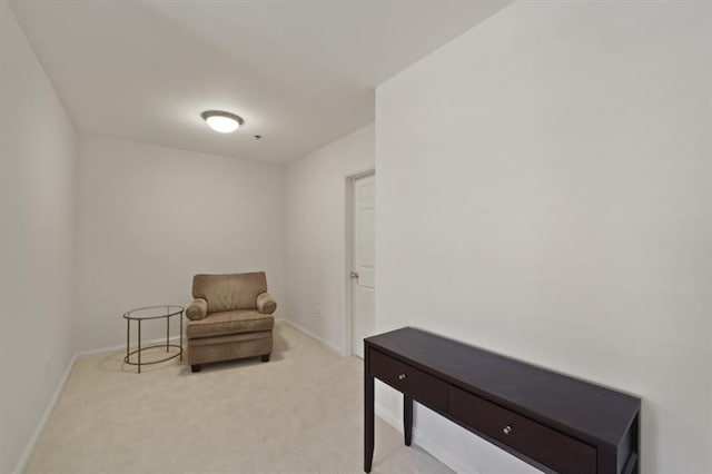 sitting room featuring light colored carpet and baseboards