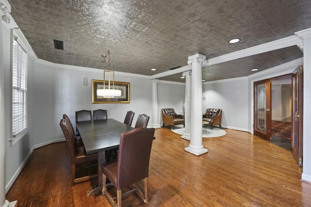 dining area featuring baseboards, wood finished floors, and ornate columns