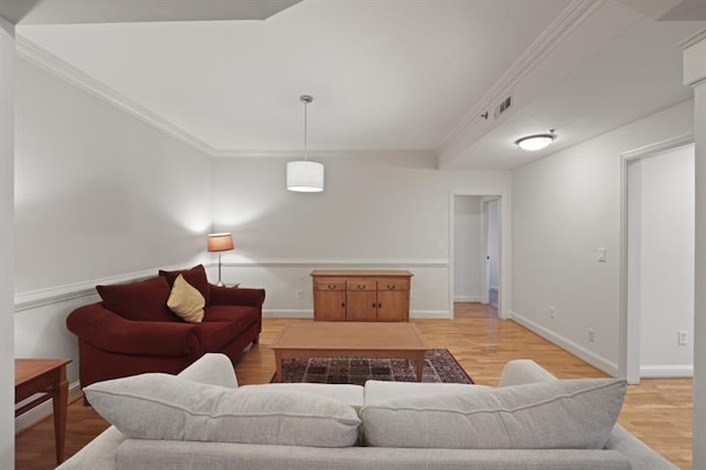 living area with ornamental molding, light wood-type flooring, visible vents, and baseboards