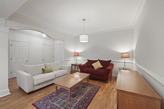 living room with ornamental molding, light wood-style flooring, and baseboards